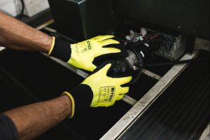 Trabajador utilizando guantes de protección térmica NITREX 360FCT amarillos y negros en entorno industrial