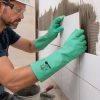 Operario colocando azulejos con guantes Nitrex 613 resistentes a productos químicos y humedad