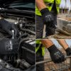 Operario de construcción colocando bloques de hormigón con guantes negros NITREX 290B en una obra y mecanica de automovil.”
