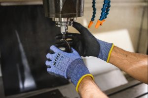 guante anticorte Nitrex 241PC18 manipulando pieza mecánica en maquinaria industrial