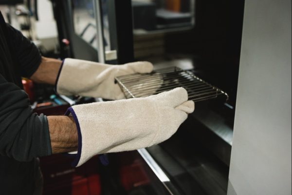 Operario utilizando guantes térmicos anti-calóricos NITREX para manipular bandejas calientes en horno industria