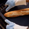 Operario utilizando guantes NITREX 281 anti-calóricos con puntos de nitrilo para manipular bandejas calientes de pan en horno industrial
