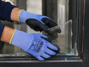 Trabajador utilizando guantes anticorte Nitrex 241NF manipulando cristal roto con alta protección al corte