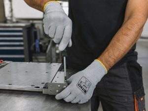 Trabajador usando guantes anticorte Nitrex 245P realizando montaje y ajuste de piezas metálicas con destornillador