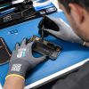 Técnico realizando reparación de smartphone con guantes anticorte Nitrex 221RF de alta precisión y compatibilidad táctil.