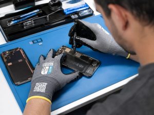 Técnico realizando reparación de smartphone con guantes anticorte Nitrex 221RF de alta precisión y compatibilidad táctil.
