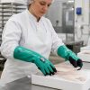 Trabajadora del sector alimentario utilizando guantes Nitrex 460 aptos para contacto alimentario durante manipulación de pescado fresco