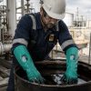 Operario petroquímico utilizando guantes largos Nitrex 460 resistentes a aceites, químicos y disolventes en entorno industrial