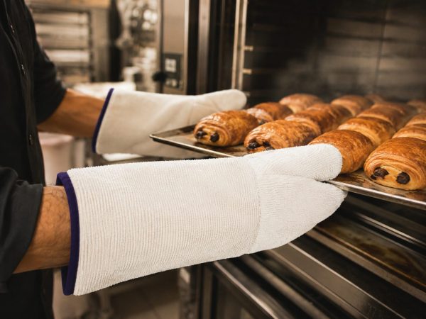 Guantes NITREX 280 de protección térmica NITREX manipulando bandeja de bollería caliente en horno de panadería
