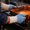 Trabajador utilizando guantes NITREX 281 anti-calóricos para manipular moldes y piezas metálicas calientes en industria