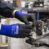 Operario trabajando con maquinaria industrial usando guantes NITREX 270NFP.