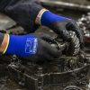 Trabajador manipulando engranajes aceitosos con guantes NITREX 270NFP.