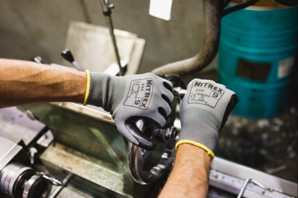 guante Nitrex 250 manipulando maquinaria en entorno industrial húmedo