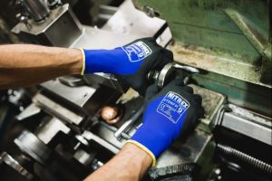 Operario manipulando tornillos y piezas metálicas con guantes NITREX 270NFP