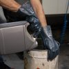 Operario utilizando guantes de nitrilo azul Nitrex 420 para manipular productos químicos y aceites en un bidón.
