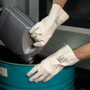 Guante industrial Nitrex 420BL de color blanco en pleno trasvase de líquidos desde una garrafa.
